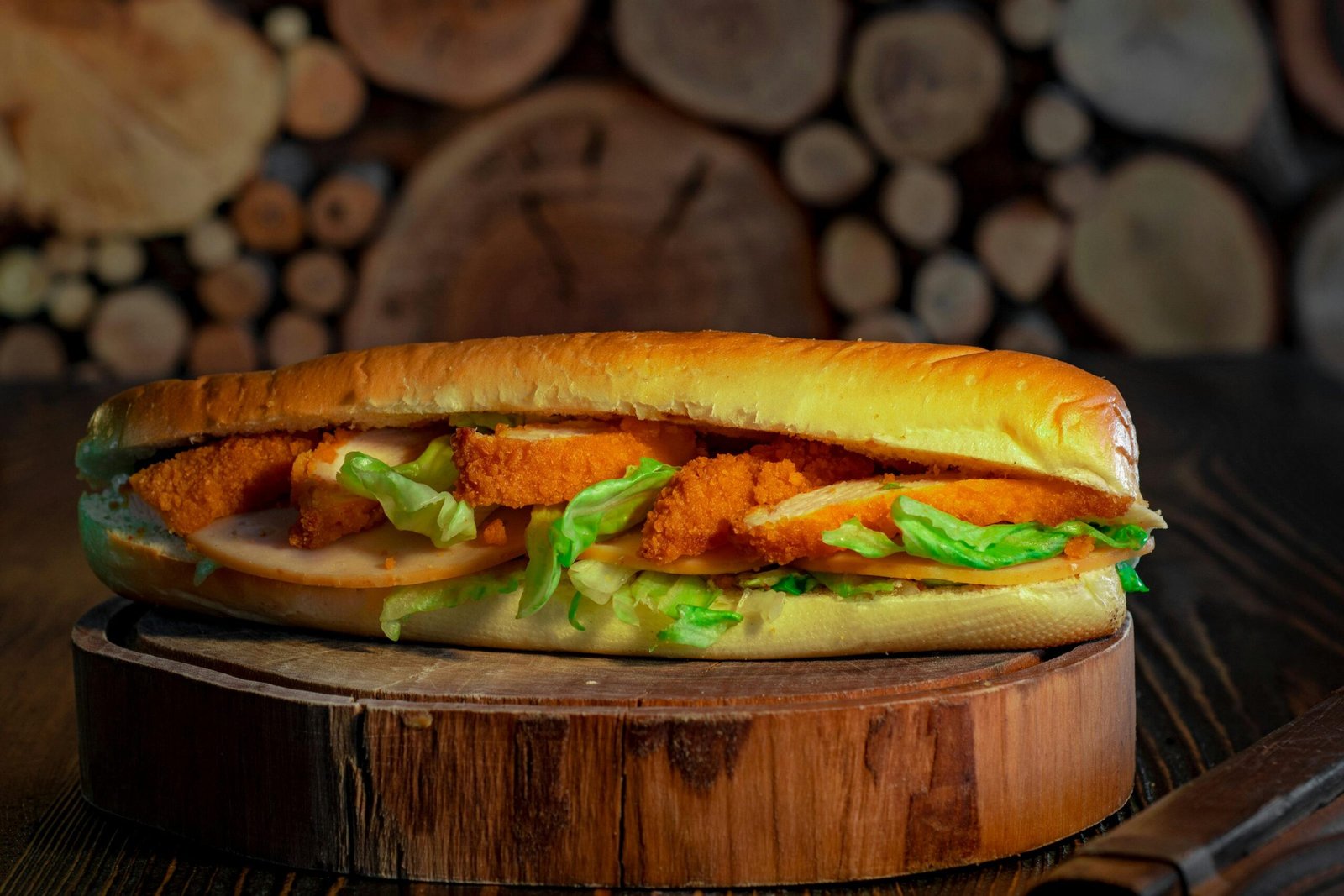 Close-up of a crispy chicken sandwich with fresh lettuce on a wooden board, perfect for a tasty meal.